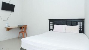 A bedroom with a bed, a desk, a chair, and a TV mounted on the wall. - Citra Homestay Soe (Soe City)