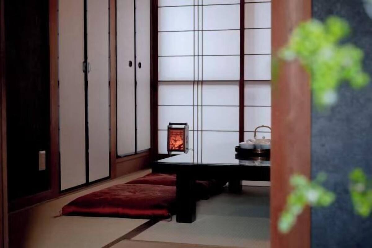 Una habitación tradicional japonesa con suelo de tatami, puertas correderas, una mesita baja y un farol.