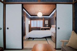 A traditional Japanese-style room with tatami flooring, a low wooden desk, a bed, and sliding doors. - Gion Donguri An (Kyoto)