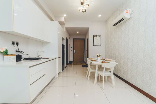 A modern kitchen with white cabinetry, a dining area with a white table and chairs, and an air conditioning unit on the wall.