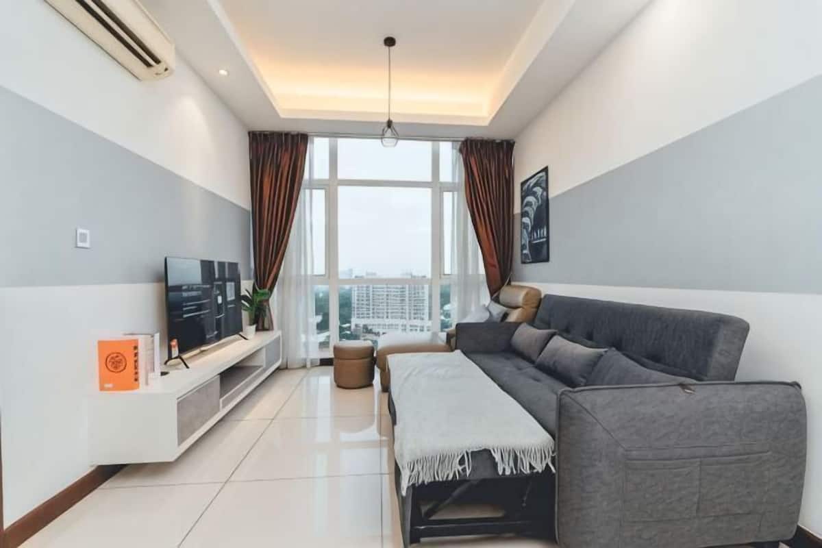 A modern living room with a sofa, TV, and a window with curtains.