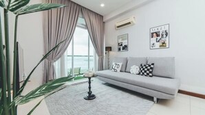 A modern living room with a grey sofa, a patterned rug, and a large window with curtains. - Paragon Residence Johor Bahru (Johor Bahru)