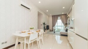 A modern living room with a dining area, a sofa set, and a large window with curtains. - Paragon Residence Johor Bahru (Johor Bahru)
