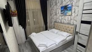 A neatly made bed with white linens, a wall-mounted TV, and a beach-themed picture. - Shosh Garden Family Resort (Bostanlik District)