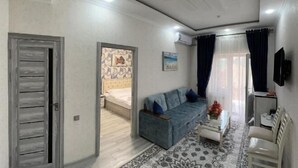 A modern living room with a sofa, a coffee table, and a TV mounted on the wall. - Shosh Garden Family Resort (Bostanlik District)