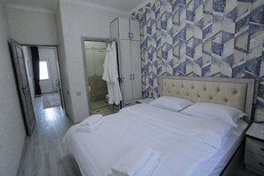 A hotel room with a bed, a wardrobe, a bathroom, and a patterned wall.