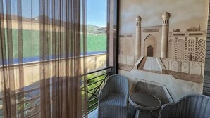 A balcony with sheer curtains, a mural of a mosque, and two wicker chairs. - Shosh Garden Family Resort (Bostanlik District)