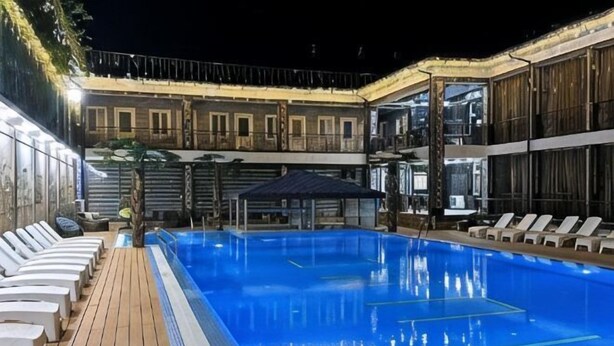 A swimming pool with lounge chairs, a wooden deck, and a covered seating area. - Shosh Garden Family Resort (Bostanlik District)