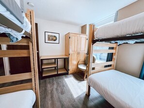 A bunk bed room with a desk, a wooden wardrobe, and a window. - 7 Beds Downtown Apt | 2BR 2BA | Large Groups (Pittsburgh)