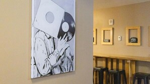 Un mur orné d’un grand tableau abstrait et un coin bar avec des tabourets.