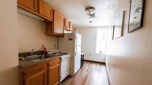 A kitchen with wooden cabinets, a stainless steel sink, a stove, and a refrigerator. - Cozy + Convenient | Downtown Apt | Walk Everywhere (Pittsburgh)