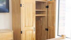 Quarto com cama, guarda-roupa de madeira e penteadeira.