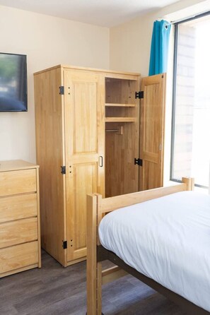 Un dormitorio con cama, armario de madera y cómoda.