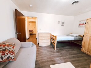 Een knus ingerichte kamer met een slaapbank, een bed, een houten garderobe en een bureau.