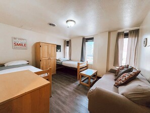 Ein gemütlicher Raum mit Bett, Holzschrank, kleinem Tisch und einer Sitzecke.