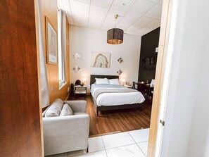 A bedroom with a bed, a chair, a nightstand, and a lamp. - Central Downtown Queen Bed | Walk to all Venues (Pittsburgh)