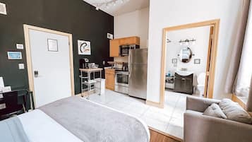 Habitación de hotel con cama, sofá, kitchenette y baño.