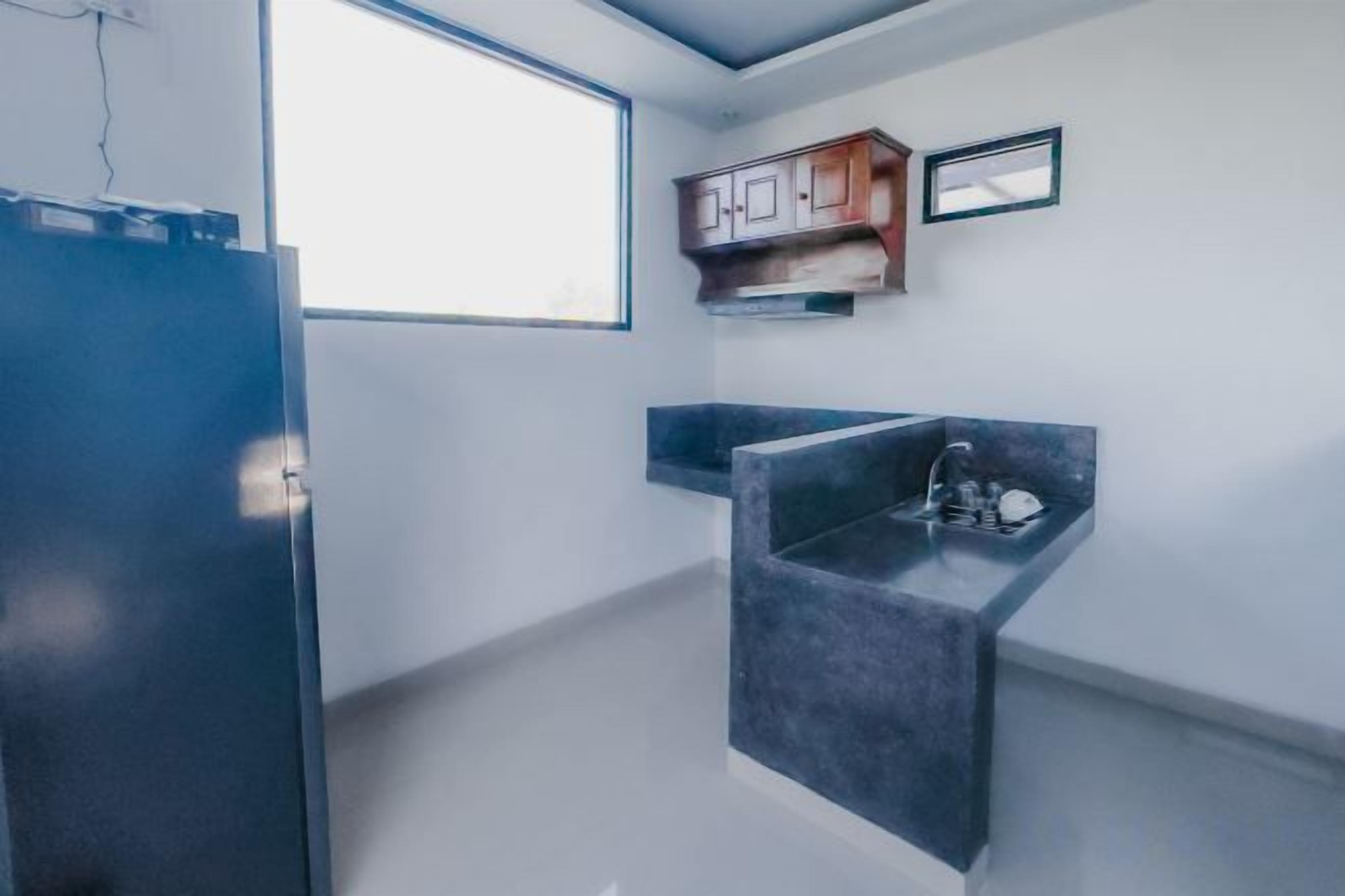 A kitchen with a built-in sink, a window, and a refrigerator.