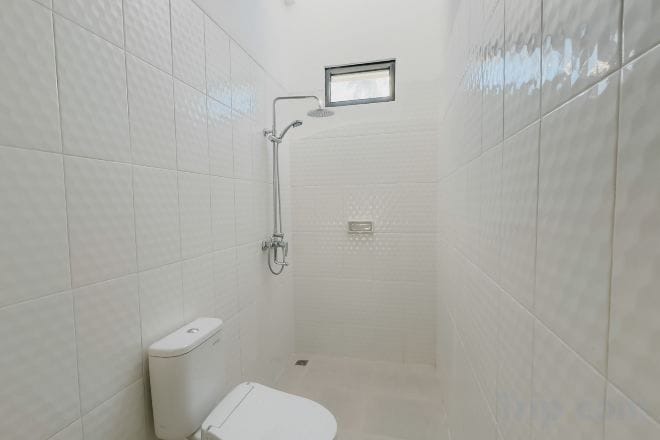 A small, enclosed shower area with a toilet and a showerhead.