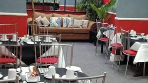 A dining area with tables set for service, a sofa in the background, and a plant. - The White Swallow Hotel (Blackpool)