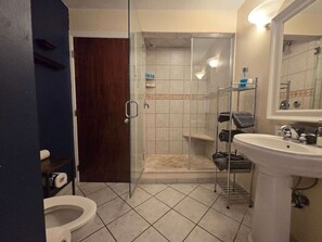 A bathroom with a toilet, sink, shower, and glass door. - Downtown Apartment | 2 Queen Beds + 60” TV (Pittsburgh)