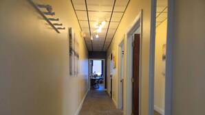 A hallway with a carpeted floor, light fixtures on the ceiling, and doors on both sides.