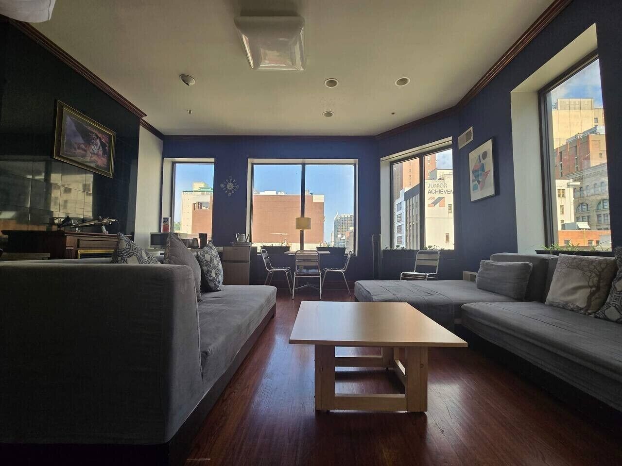 A modern living room with a sofa set, a coffee table, and a view of the city through large windows.