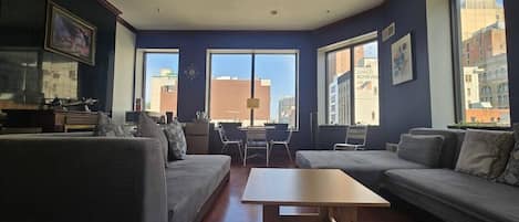 A modern living room with a sofa set, a coffee table, and a view of the city through large windows.