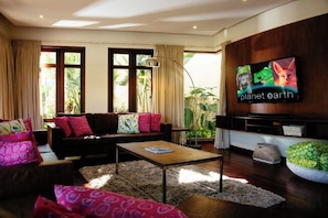 Una sala de estar con un sofá, una mesa de centro y un televisor montado en la pared.