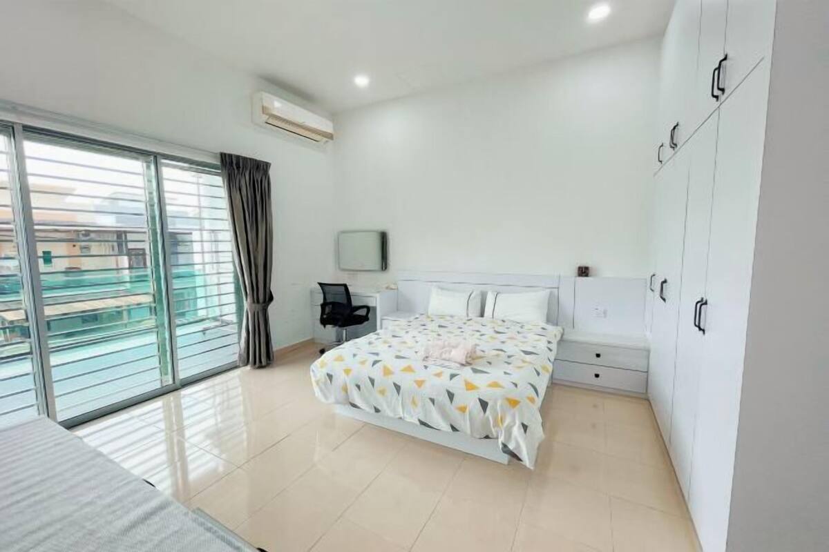 A bedroom with a bed, a desk, a chair, a wardrobe, and a window with curtains.