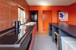 A modern kitchen with a black countertop, stainless steel sink, and a coffee machine. - VILLA + SECCA (Ito)