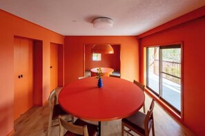 A dining area with a round table, chairs, and a vase of flowers. - VILLA + SECCA (Ito)