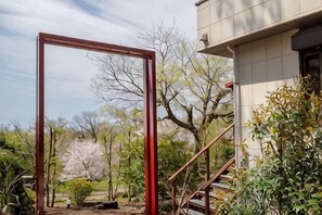 A metal structure in a garden area, a staircase, and a building with a tiled exterior. - VILLA + SECCA (Ito)