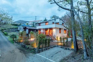 Una casa moderna de dos pisos amb fonamentació de pedra, una escala visible i una entrada ben il·luminada.