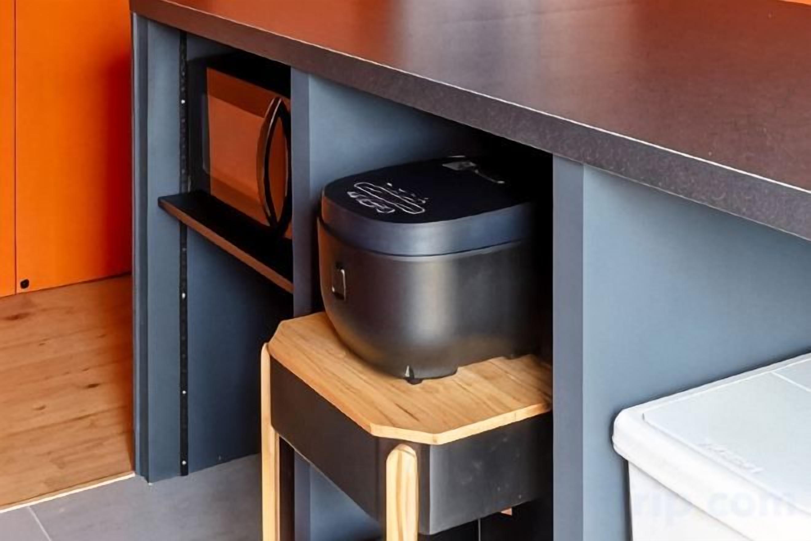 Una cocina con electrodoméstico empotrado, un taburete de madera y una unidad de cajones.