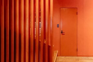 A hallway with a wooden slat partition and an orange door. - VILLA + SECCA (Ito)