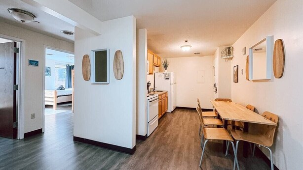 Une cuisine moderne avec des meubles en bois, une table à manger avec des chaises et un petit îlot central.