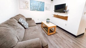 Un salon comprenant un canapé, une table basse et un téléviseur à écran plat fixé au mur.