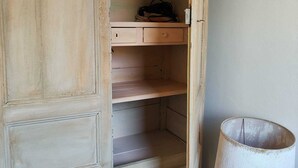 Una habitación con un armario grande y vacío, con varios estantes y una mesita pequeña.