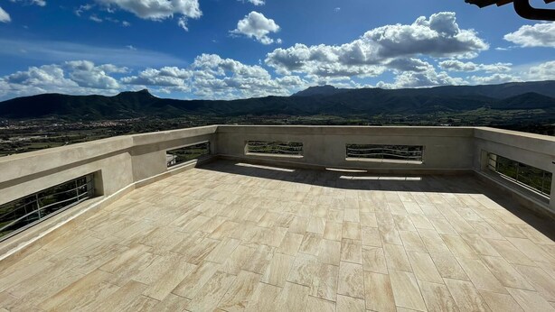 Terraza en la azotea con vistas a montañas distantes y cielo despejado.