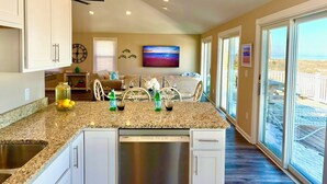 A modern kitchen with a granite countertop, a Bosch dishwasher, and a dining area with a view of the beach.