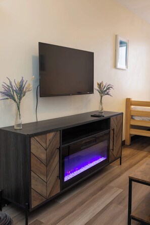 A modern living room with a flat-screen TV mounted on the wall, a built-in fish tank, and a wooden bench.