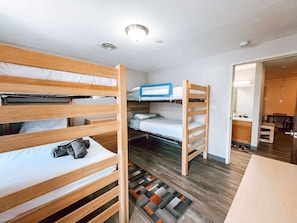 A room with bunk beds, a small table, and a kitchenette area. - 2BR 2BA Downtown Apt | Water + City Views (Pittsburgh)