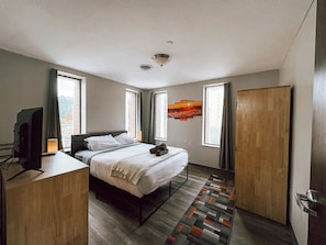 Een moderne hotelkamer met een bed, bureau, televisie en een schilderij aan de muur.