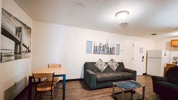 A living room with a sofa, a dining table with chairs, a small coffee table, and a refrigerator in the background. - Spacious 2BR/2BA Downtown Apt|Clean and Safe| (Pittsburgh)