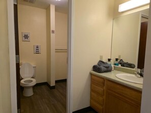 A hotel bathroom with a toilet, sink, and wooden cabinets.