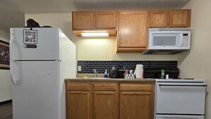 A kitchen with wooden cabinets, a white refrigerator, a microwave, and a stove. - Cozy Downtown Pittsburgh Apartment | Smart TV + Wa (Pittsburgh)