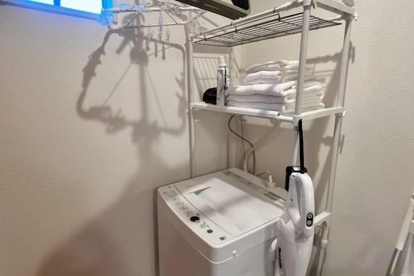 A laundry area with a washing machine and a drying rack. - Senju Kotobuki 2,3F (Tokyo)