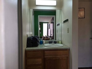 A bathroom with a sink, mirror, and wooden cabinets. - Downtown Apt | Queen Bed + 60” Smart TV (Pittsburgh)