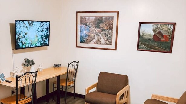 A living room with a wooden coffee table, two brown sofas, a dining table with chairs, and three framed pictures on the wall. - 2BR 2BA Downtown Apt | Spacious + Walkable (Pittsburgh)